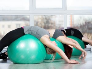 fit ball stretch exercise for entire back laying center of back on ball relaxed with arms stretched overhead