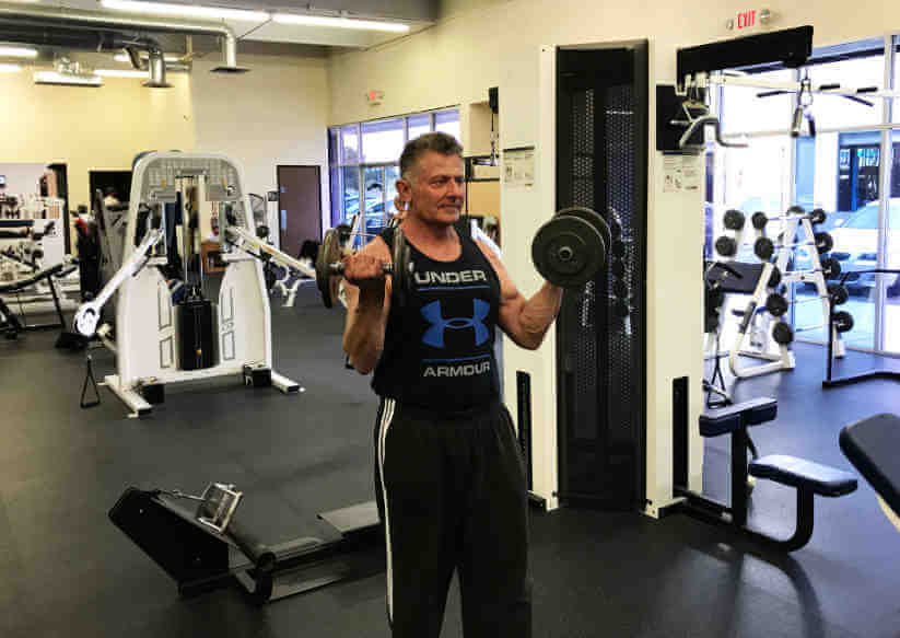 personal trainer performing curls with dumbbells in a gym