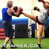 instructor holding pads while client performs a roundhouse kick