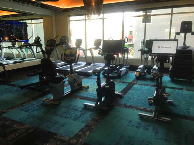 Cardio equipment room in apartment gym with windows overlooking the pool