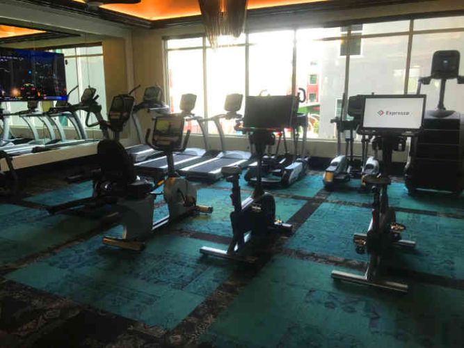 Cardio equipment room in apartment gym with windows overlooking the pool