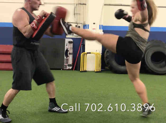 girl front kicking a thai pad while instructor holds the pads
