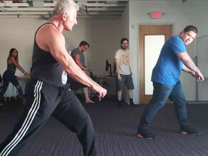 people performing a tension exercise by tensing and dynamically pulling and pushing arms forward and back