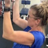 woman pulling a lat machine bar down while working out