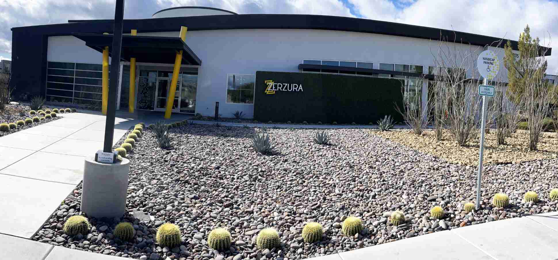 front of apartment building with na,me zerzura on it with rocks and some porcupine cactus style landscaping