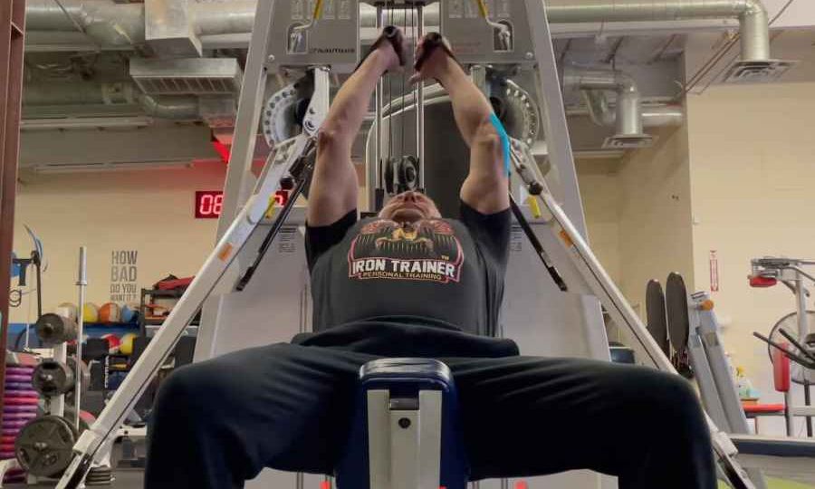 personal trainer on an incline bench performing a cable exercise for chest