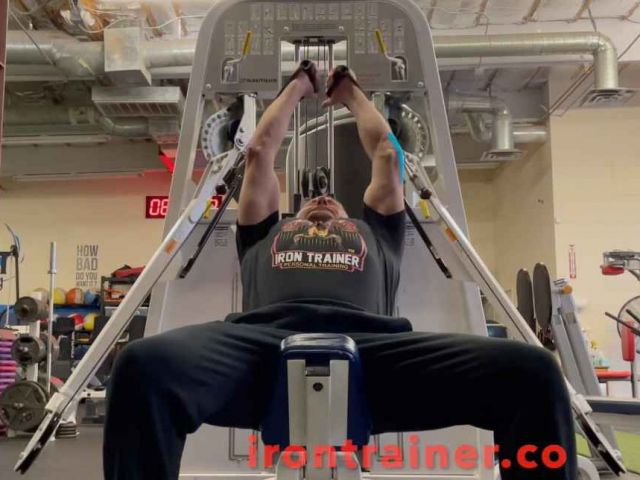 personal trainer on an incline bench performing a cable exercise for chest