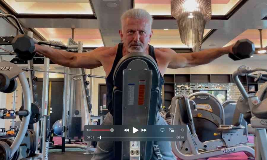 fitness trainer raising dumbbells to side