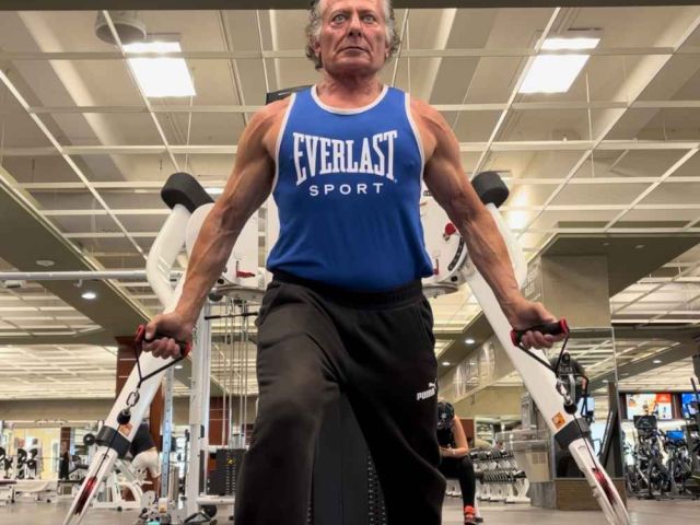 fitness expert holding a cable in each hand palms facing forward to raise cables in front for a chest and shoulder exercise