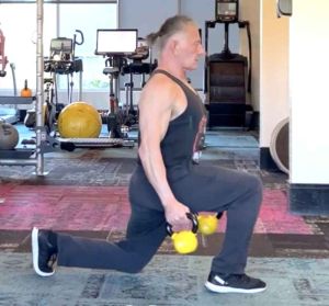 fitness trainer performing a lunge with yellow kettlebells in each hand